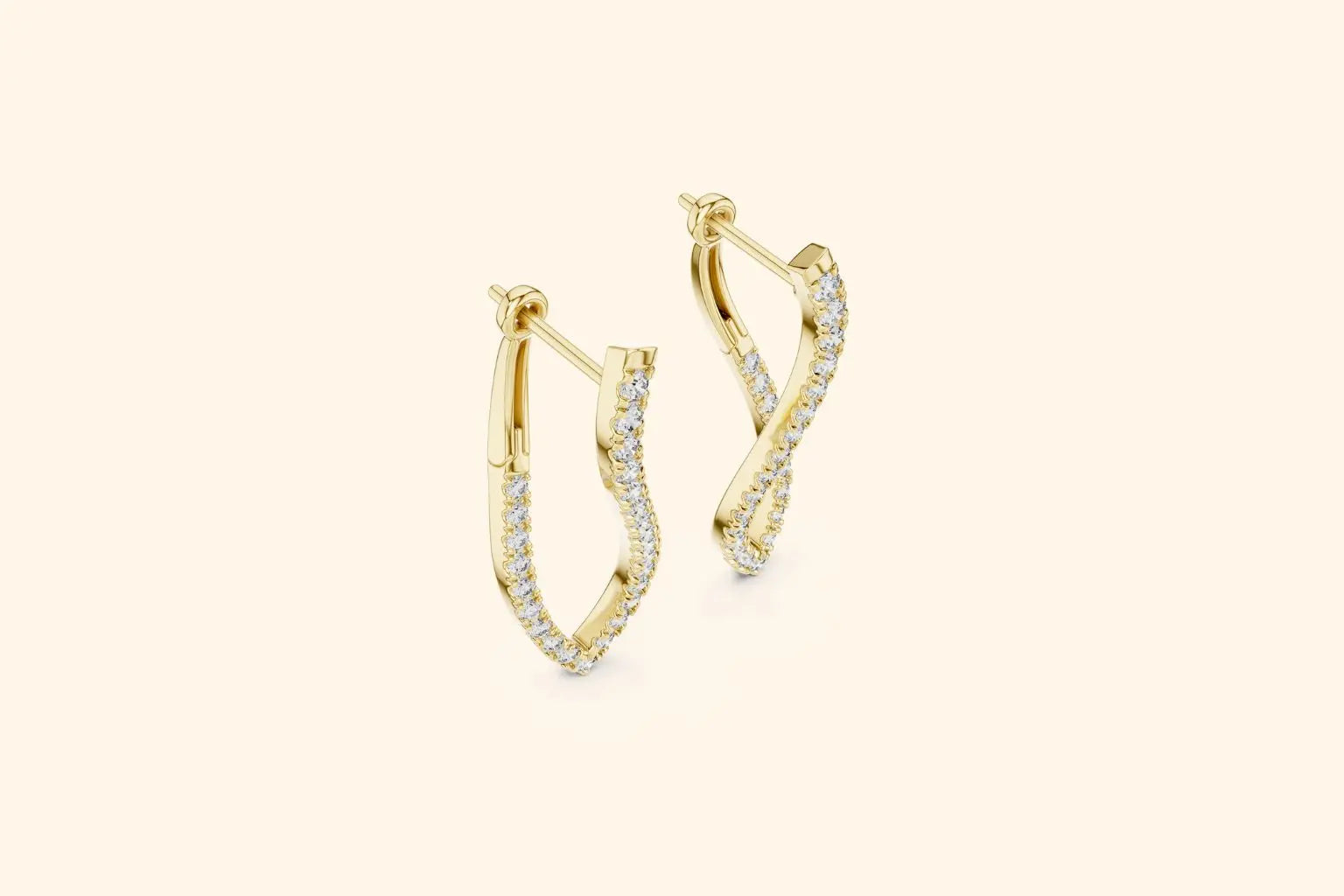 Pair of yellow gold twisted diamond drop earrings with pave setting on a soft cream background