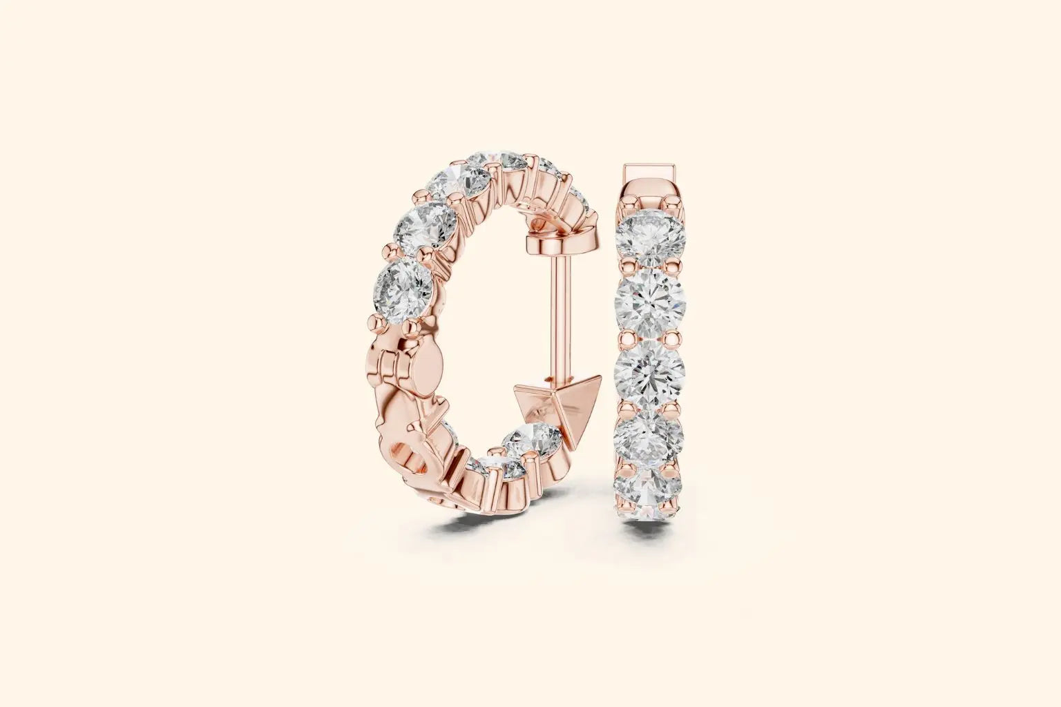 Pair of rose gold large round diamond eternity hoop earrings with gallery setting on a pale background