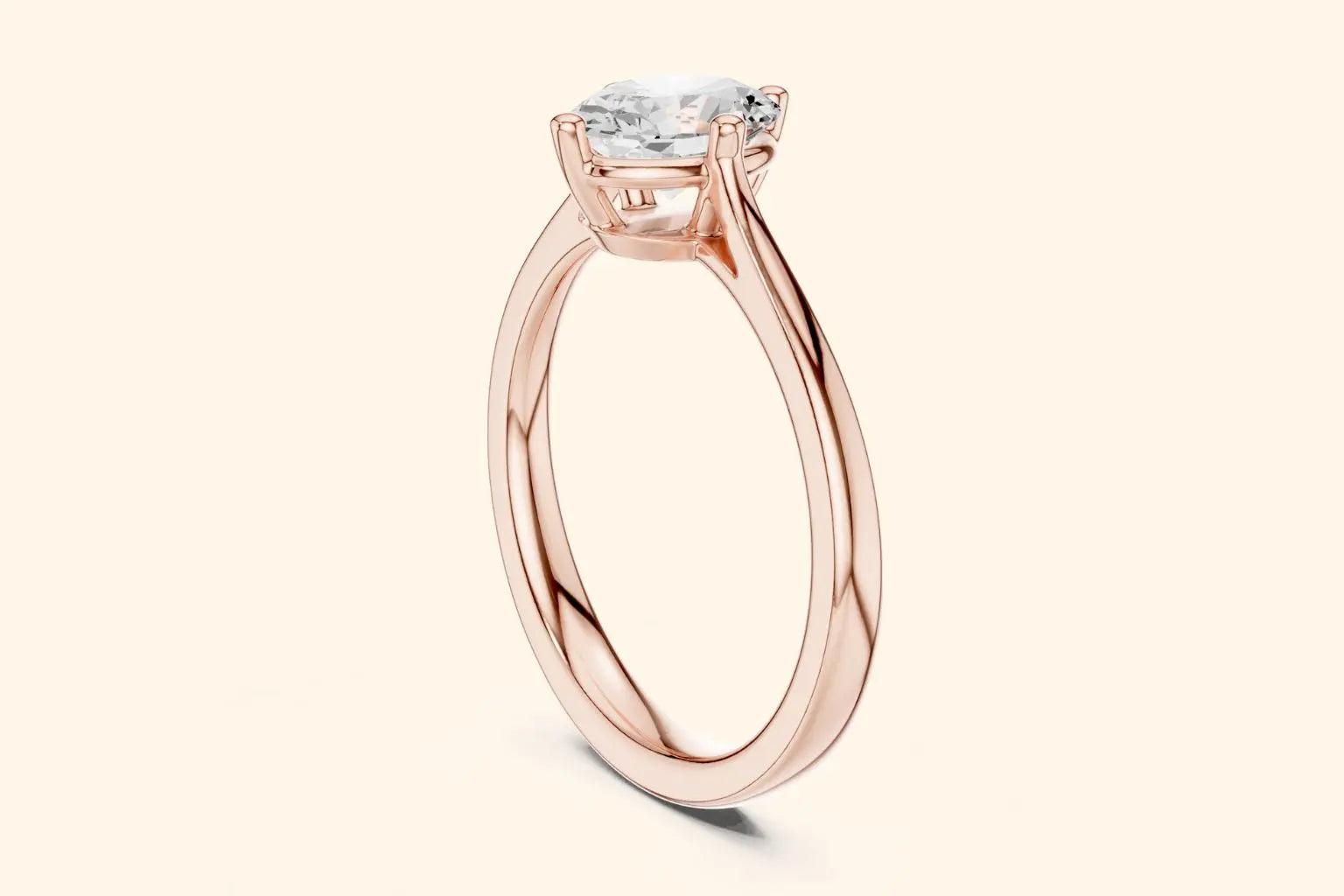 A side view of a simple, thin, polished rose gold ring band flowing up to a high-set, four-prong solitaire setting.