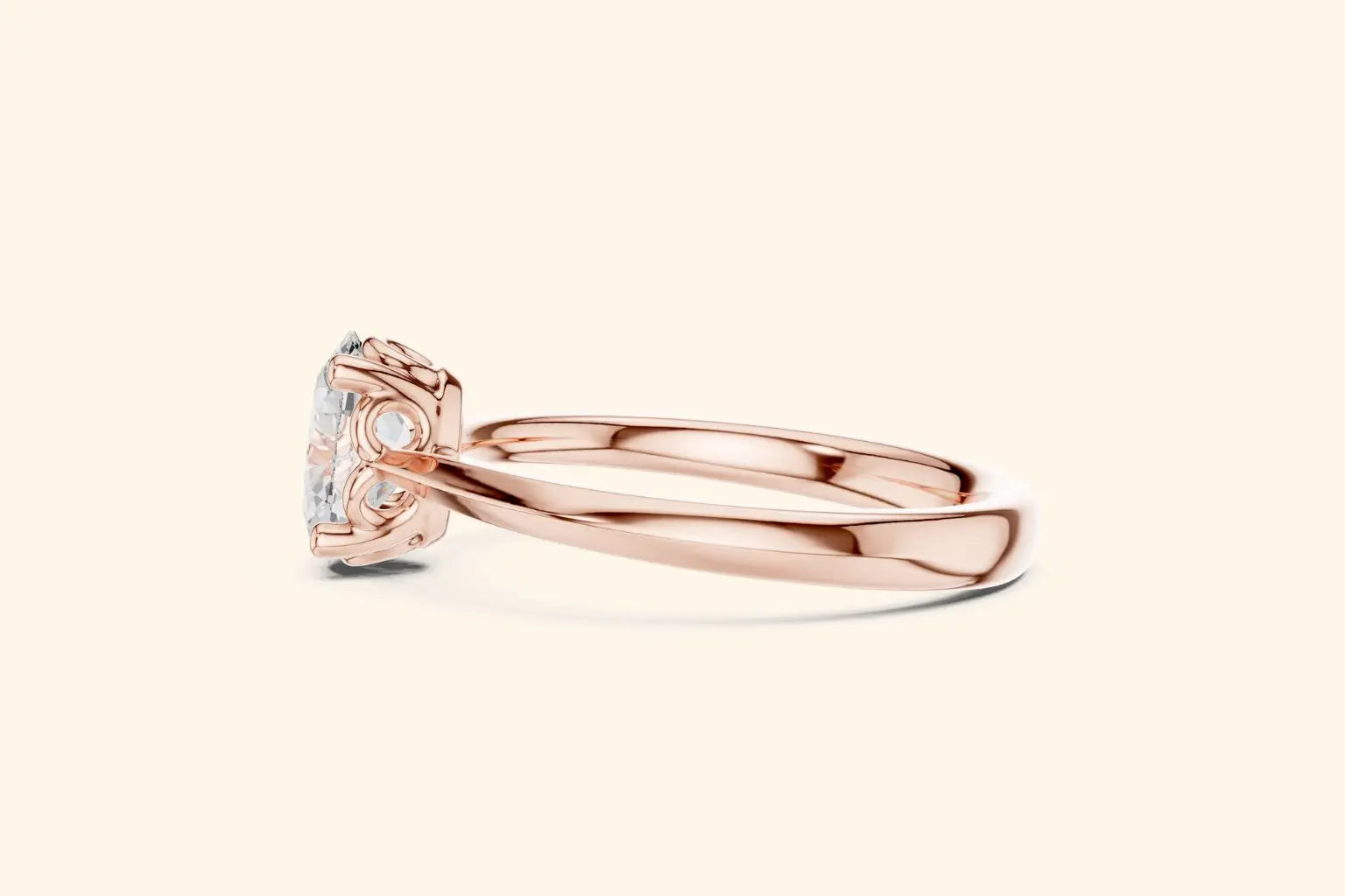 Side profile view of a polished rose gold engagement ring, showcasing the smooth band and the ornate, six-prong basket setting holding the oval diamond.
