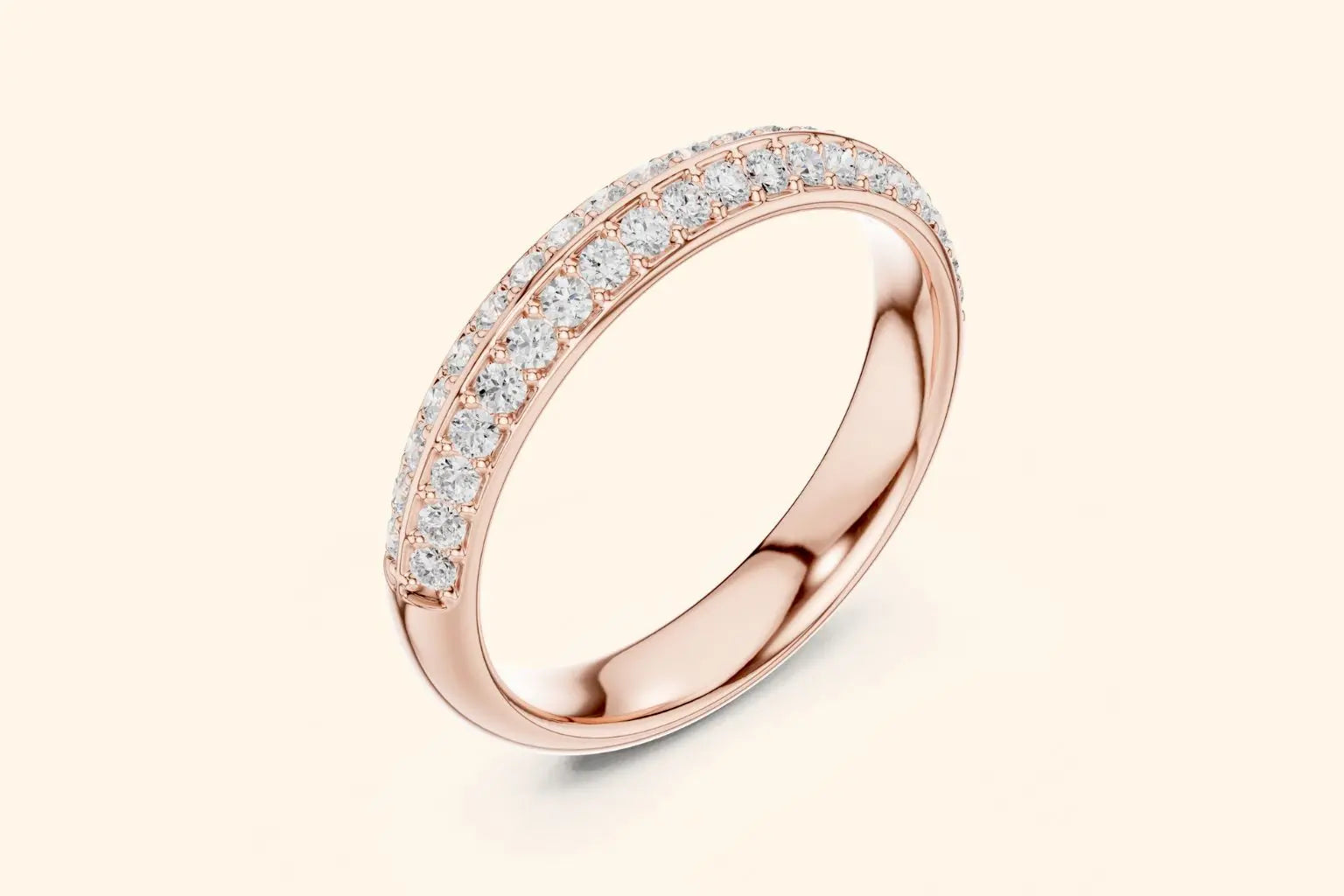 A slender, highly reflective rose gold band ring shown at an angle, with two continuous rows of closely-set round brilliant diamonds running along the outer edge. The inner surface of the band is smooth and polished.