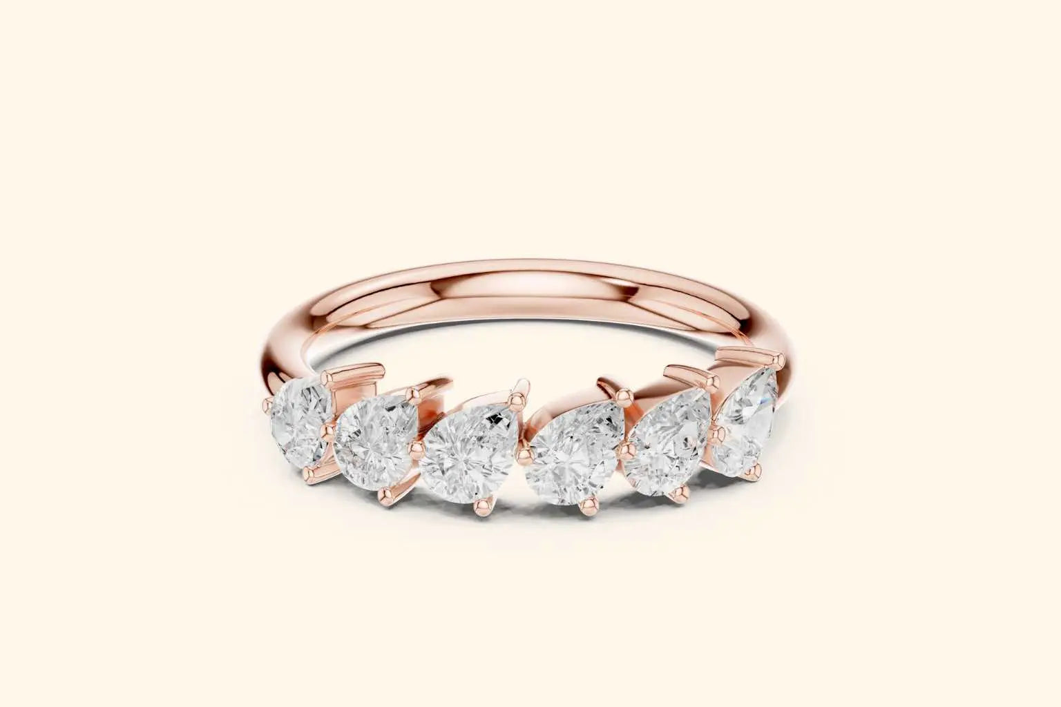 A front view of a half-band ring in polished rose gold. It features a row of six brilliant pear-shaped diamonds set horizontally along the top, with the pointed ends of the diamonds aligned in the same direction.