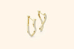 Pair of yellow gold twisted diamond drop earrings with pave setting on a soft cream background