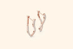 Pair of rose gold twisted infinity diamond drop earrings with pave setting on a pale background