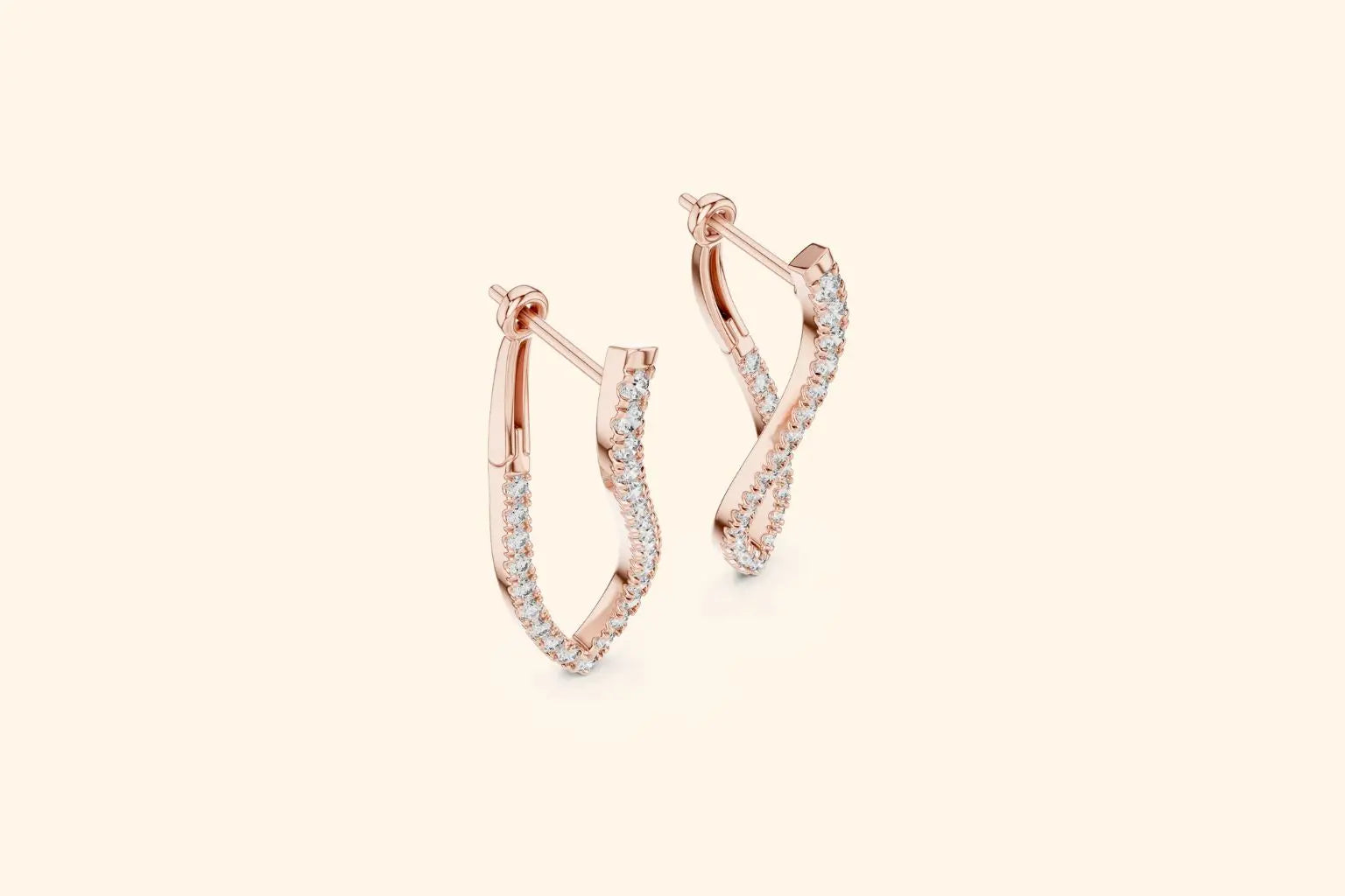 Pair of rose gold twisted infinity diamond drop earrings with pave setting on a pale background