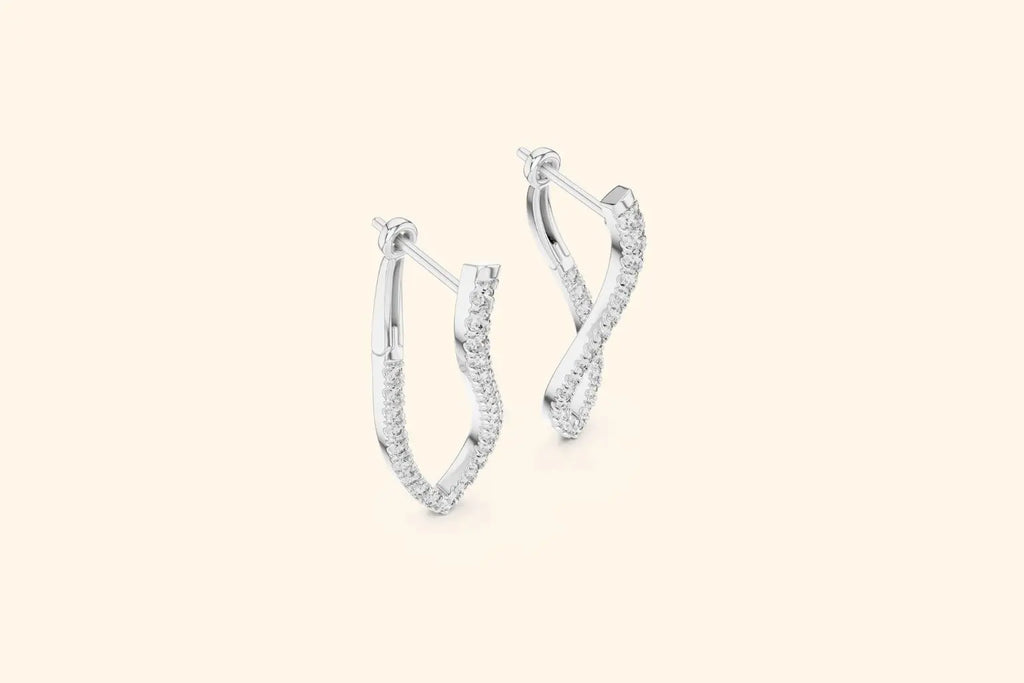 Pair of white gold twisted V-shape diamond drop earrings with pave setting on a pale background