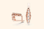 Rose gold hoop earrings with diamond accents on a light beige background
