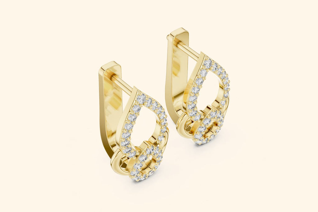 Gold hoop earrings with diamond accents on a light beige background