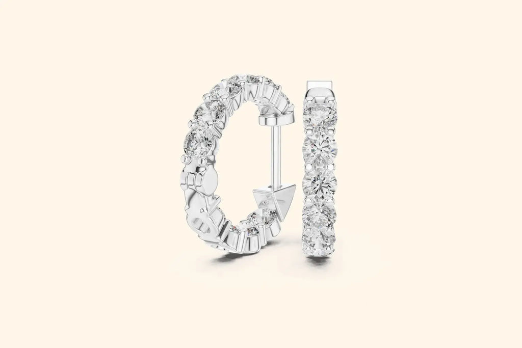 Pair of white gold large round diamond eternity hoop earrings with gallery setting on a pale background