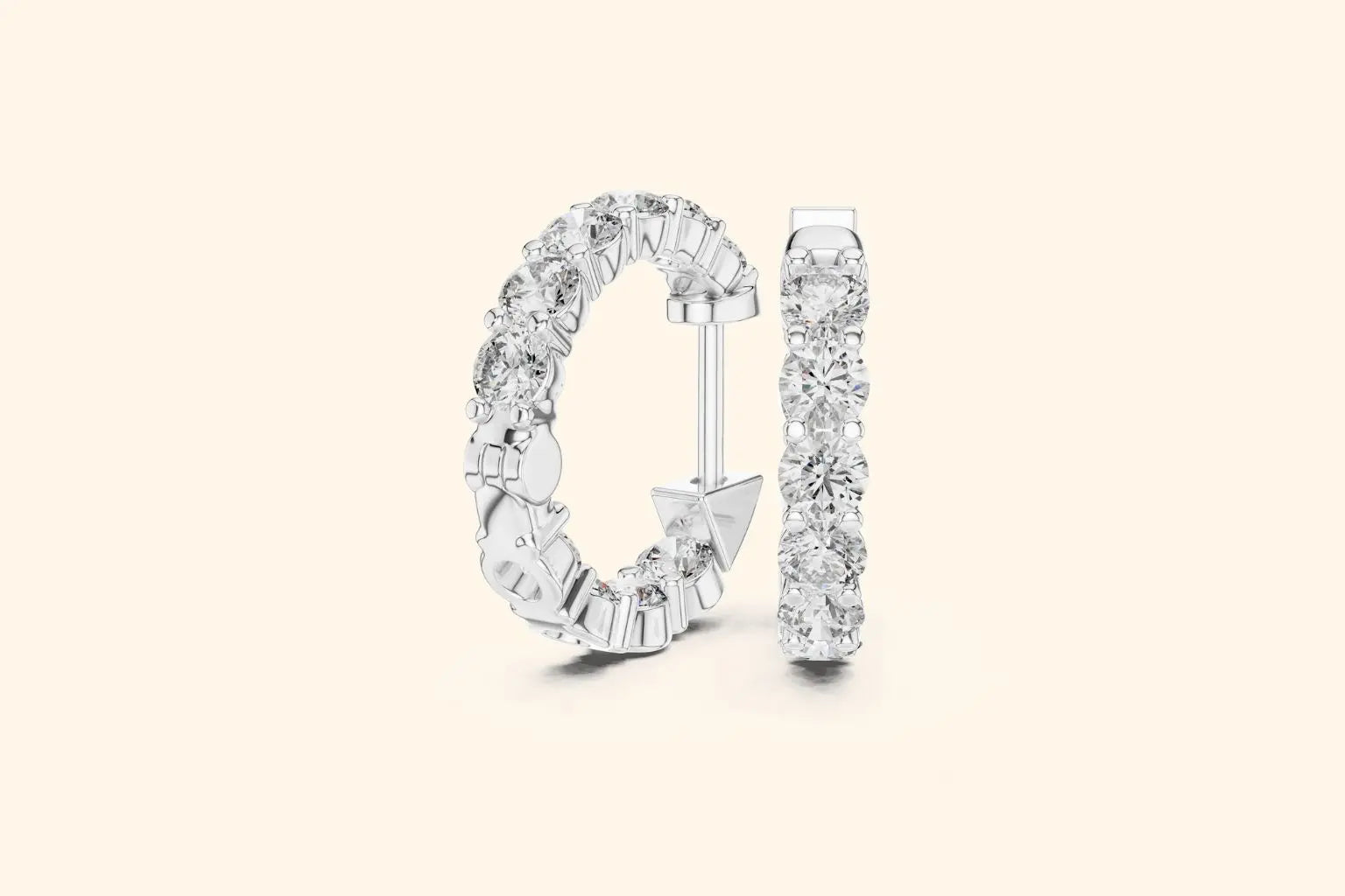 Pair of white gold large round diamond eternity hoop earrings with gallery setting on a pale background