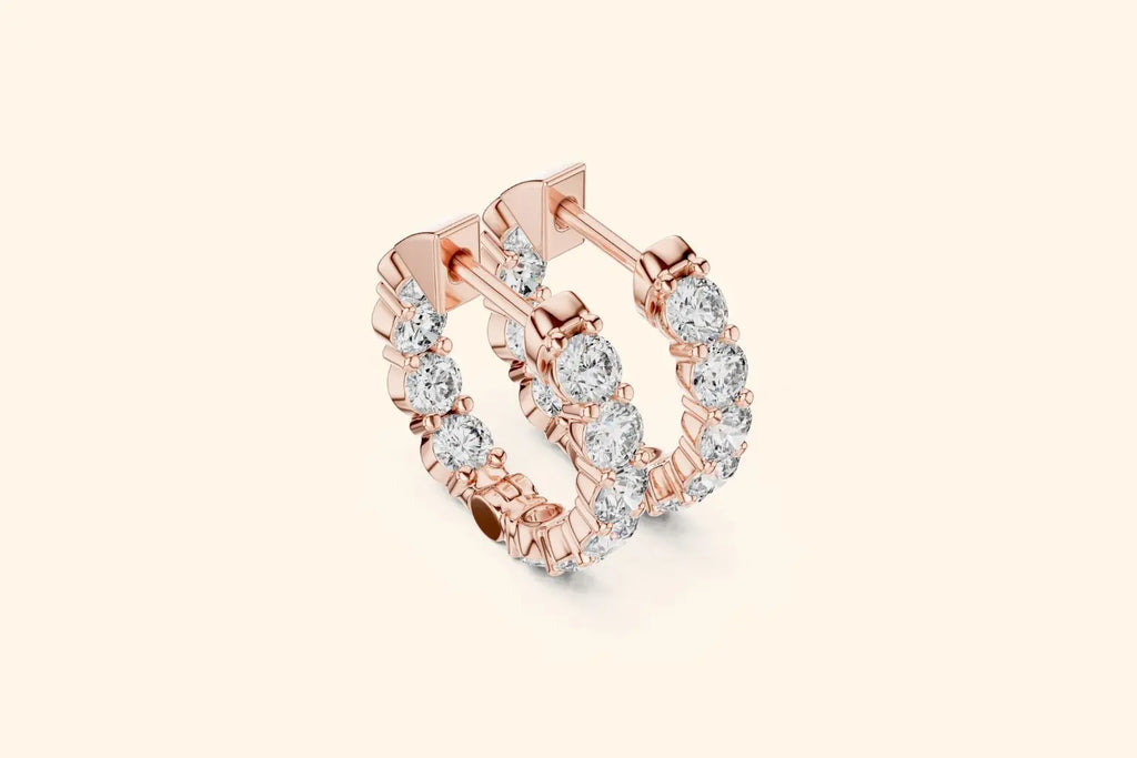 Rose gold hoop earrings with clear gemstones on a light beige background
