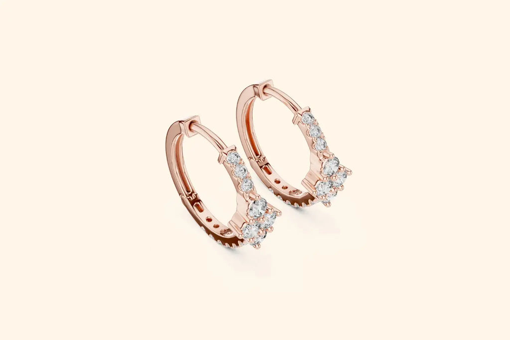 Rose gold hoop earrings with clear gemstones on a light beige background