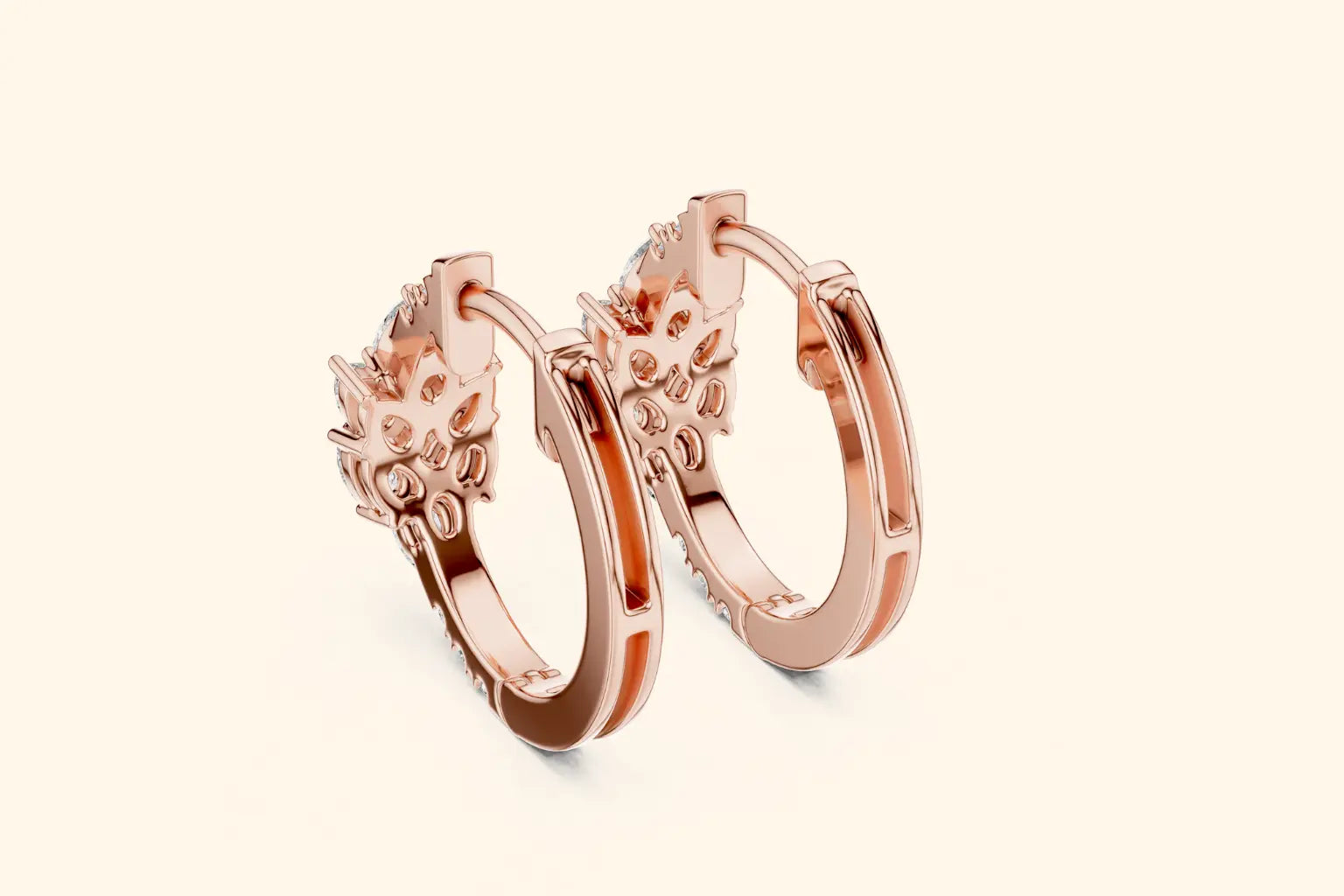 Rose gold hoop earrings with floral designs on a light beige background