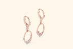 Rose gold earrings with small diamonds on a light beige background
