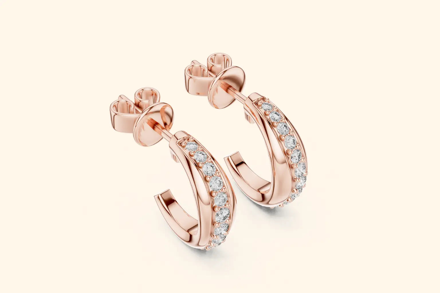 Rose gold hoop earrings with clear gemstones on a light beige background