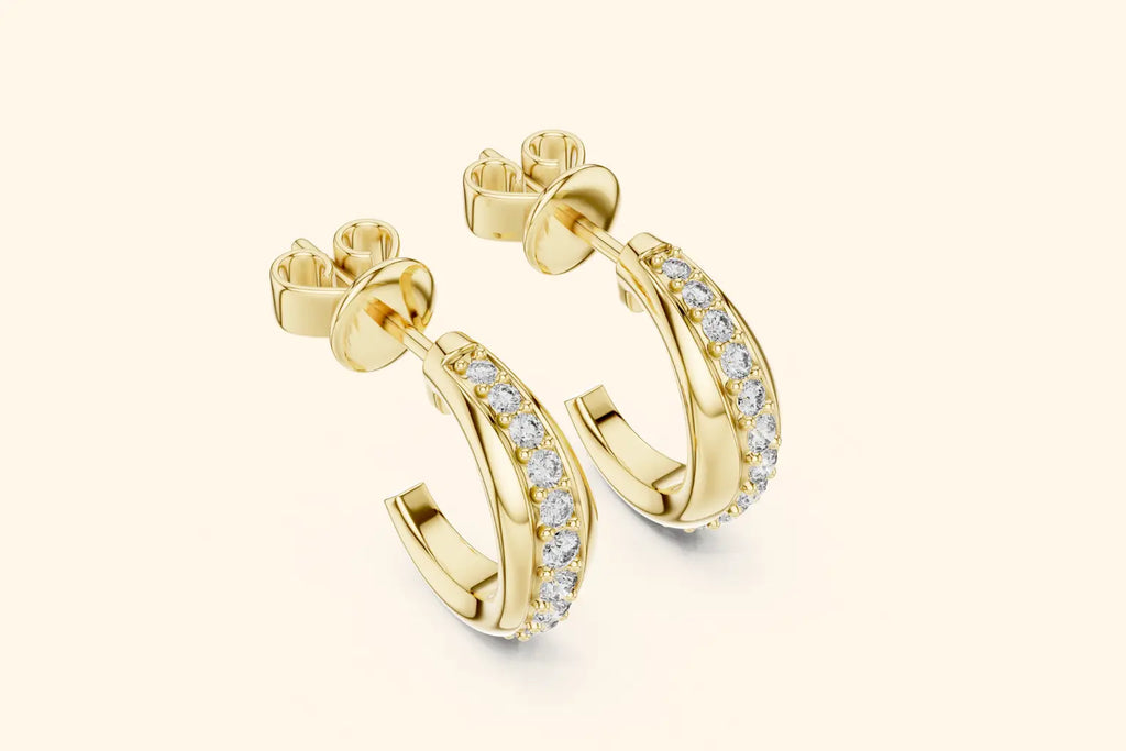 Gold hoop earrings with diamond accents on a light beige background