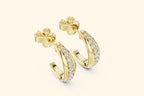 Gold hoop earrings with diamond accents on a light beige background