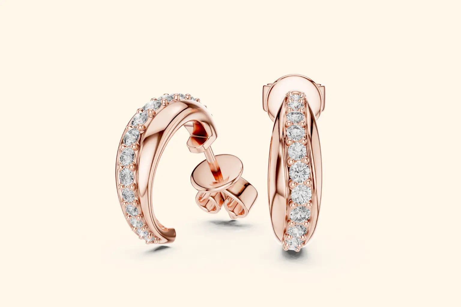 Rose gold hoop earrings with clear gemstones on a light beige background