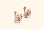 Rose gold earrings with diamond accents on a light beige background