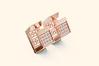 Rose gold bracelet with diamond accents on a light beige background