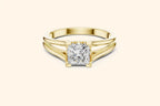 Front view of a yellow gold solitaire engagement ring with a radiant-cut diamond set horizontally in a bezel or partial bezel setting, featuring a minimalist split-shank band.