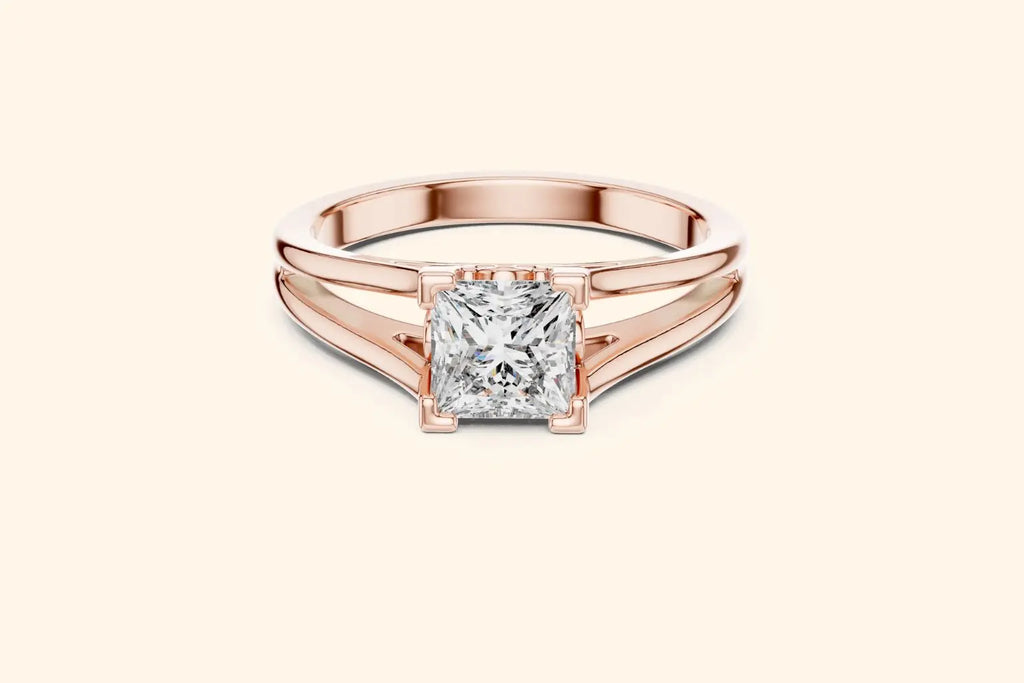 Front view of a rose gold solitaire engagement ring with a radiant-cut diamond set horizontally in a bezel or partial bezel setting, featuring a minimalist split-shank band.