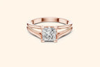 Front view of a rose gold solitaire engagement ring with a radiant-cut diamond set horizontally in a bezel or partial bezel setting, featuring a minimalist split-shank band.