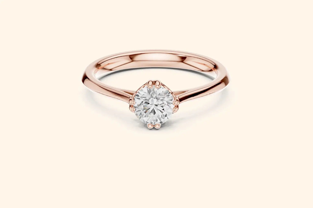Front view of a rose gold solitaire ring featuring an oval or marquise-cut diamond set horizontally in a four-prong basket on a smooth, wide, rounded band.