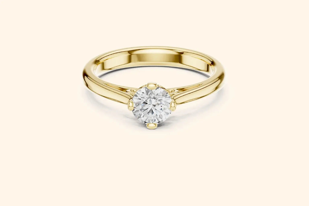 Front view of a yellow gold solitaire ring featuring an oval or marquise-cut diamond set horizontally in a four-prong basket on a smooth, wide, rounded band.