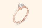 Side view of a rose gold solitaire ring featuring a round brilliant-cut diamond set in a four-prong setting with decorative filigree details under the basket, sitting atop a thin, sleek band.