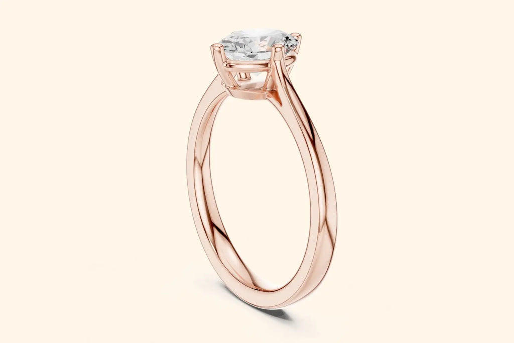 A side view of a simple, thin, polished rose gold ring band flowing up to a high-set, four-prong solitaire setting.