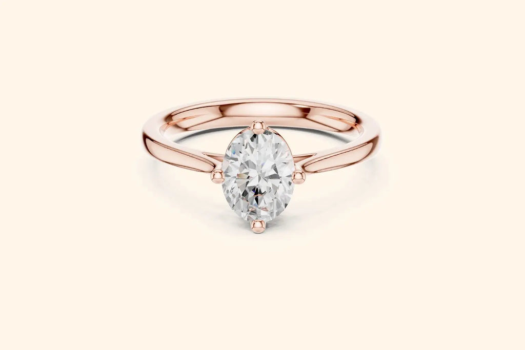 A classic solitaire engagement ring featuring an oval-cut diamond set in a sleek, four-prong compass style on a polished rose gold band.