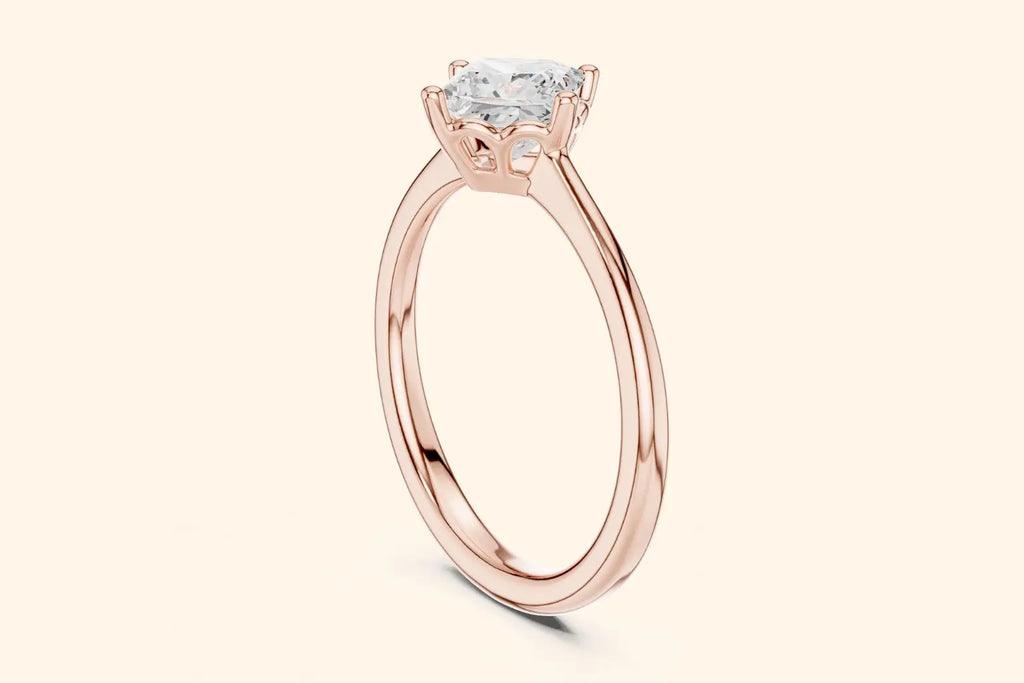 A side view of a simple, thin, polished rose gold ring band flowing up to a high-set, square diamond setting.