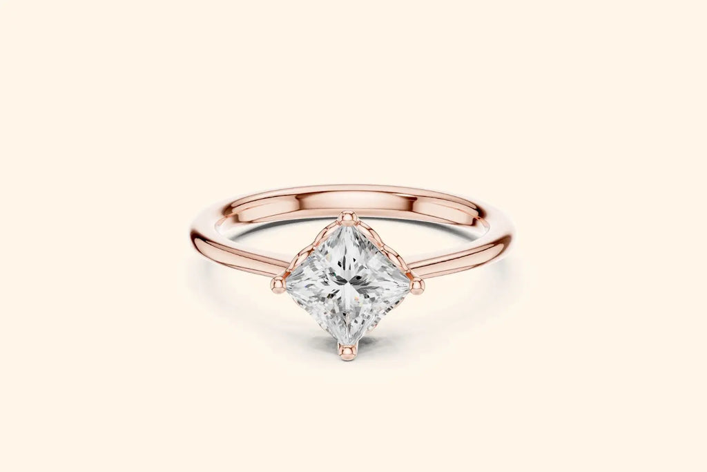 A modern solitaire engagement ring featuring a princess-cut diamond set diagonally in a four-prong setting on a polished rose gold band.
