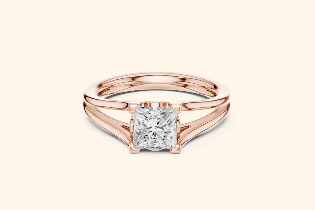 A modern solitaire ring featuring a rectangular diamond set on a wide, elegant split-shank band in polished rose gold.