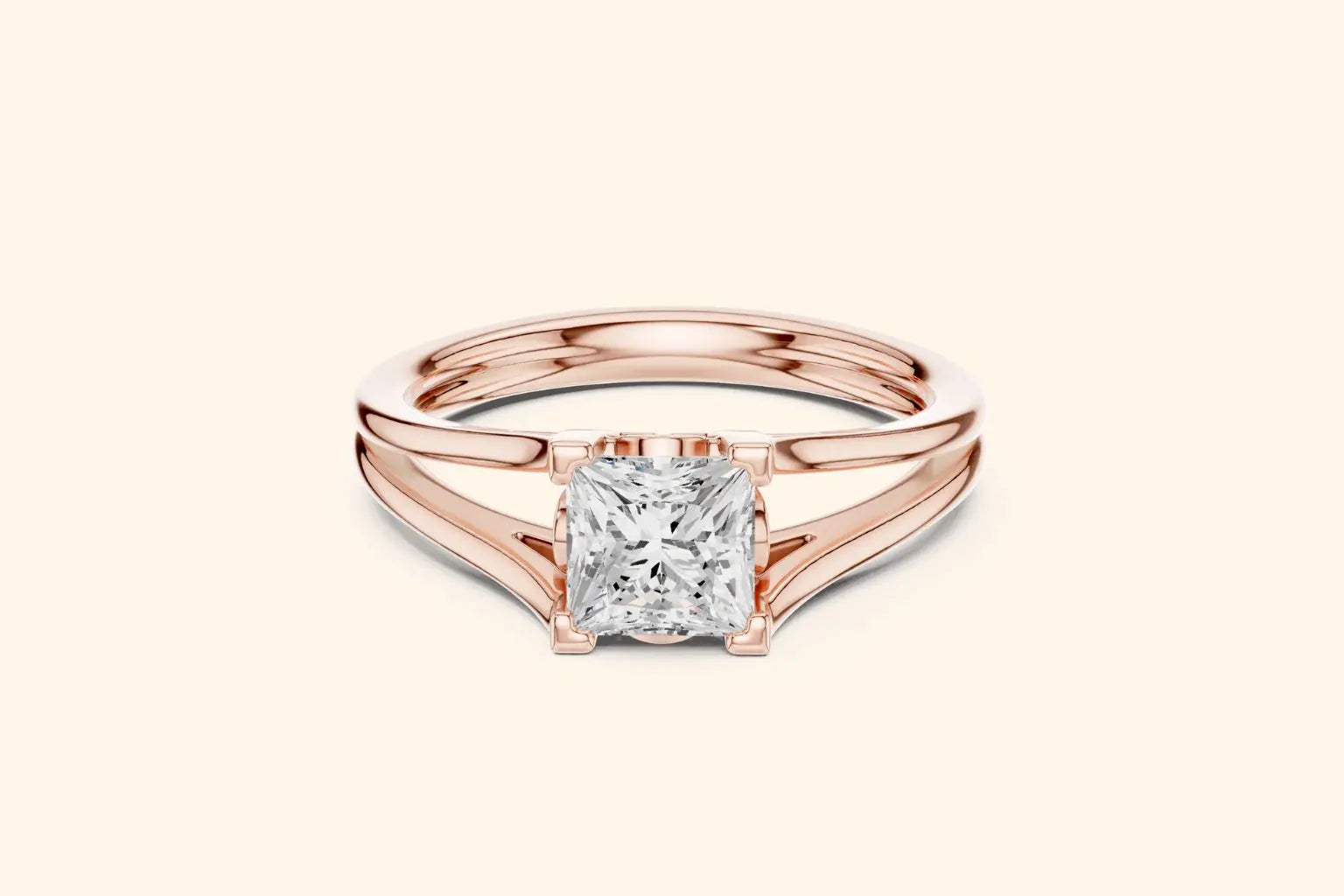 A modern solitaire ring featuring a rectangular diamond set on a wide, elegant split-shank band in polished rose gold.