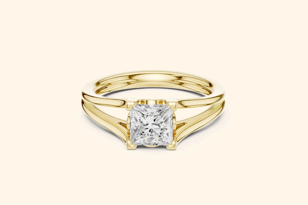 A modern solitaire ring featuring a rectangular diamond set on a wide, elegant split-shank band in polished yellow gold.