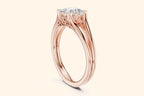 A side view of a rose gold solitaire ring, showcasing the open, split-shank band and the ornate basket setting that holds the rectangular diamond.