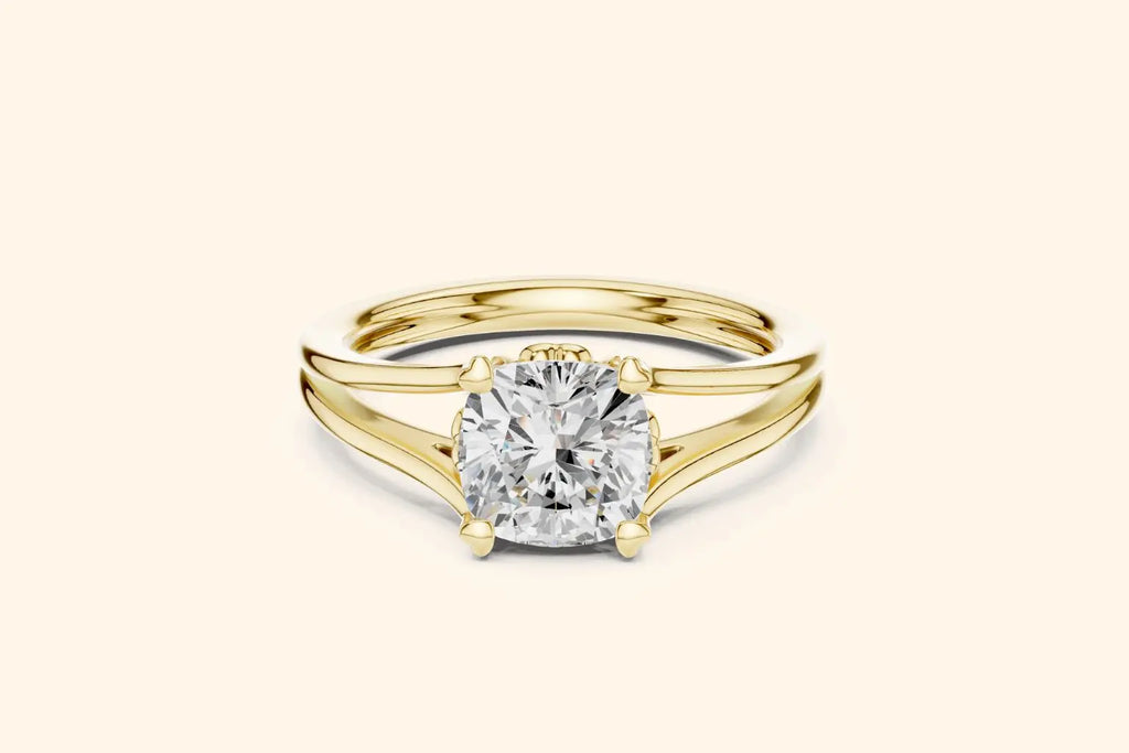 A modern solitaire ring featuring a cushion-cut diamond set on a wide, elegant split-shank band in polished yellow gold.