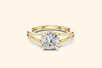 A modern solitaire ring featuring a cushion-cut diamond set on a wide, elegant split-shank band in polished yellow gold.