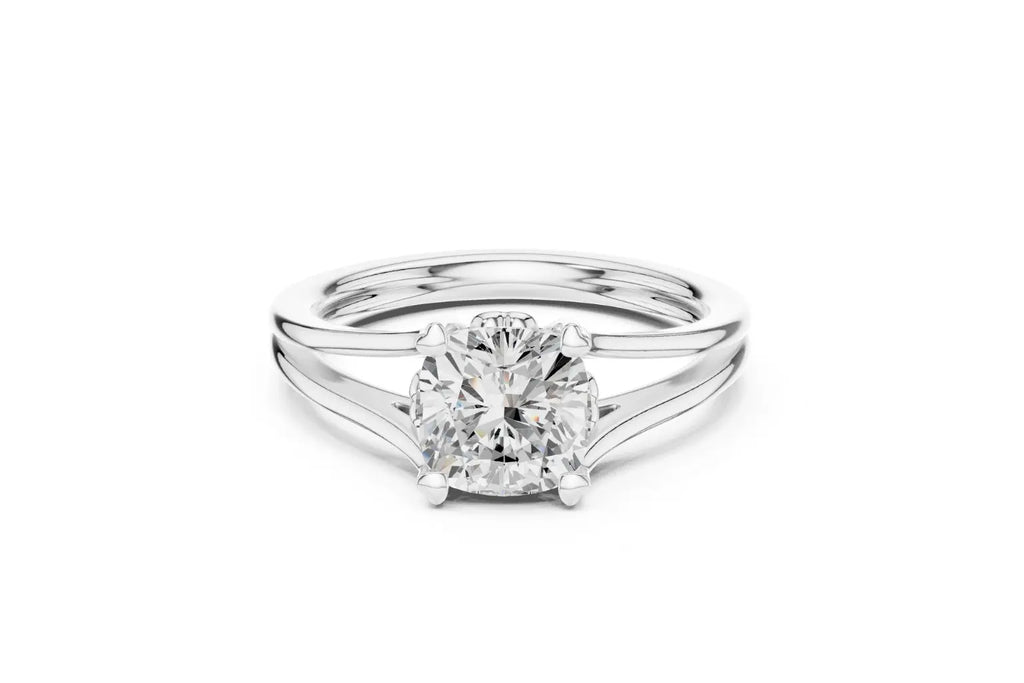 A modern solitaire ring featuring a cushion-cut diamond set on a wide, elegant split-shank band in polished white gold or platinum.