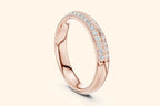 A thin, high-polished rose gold ring shown at an angle, featuring two continuous rows of brilliant round diamonds set in a pave style halfway around the band.