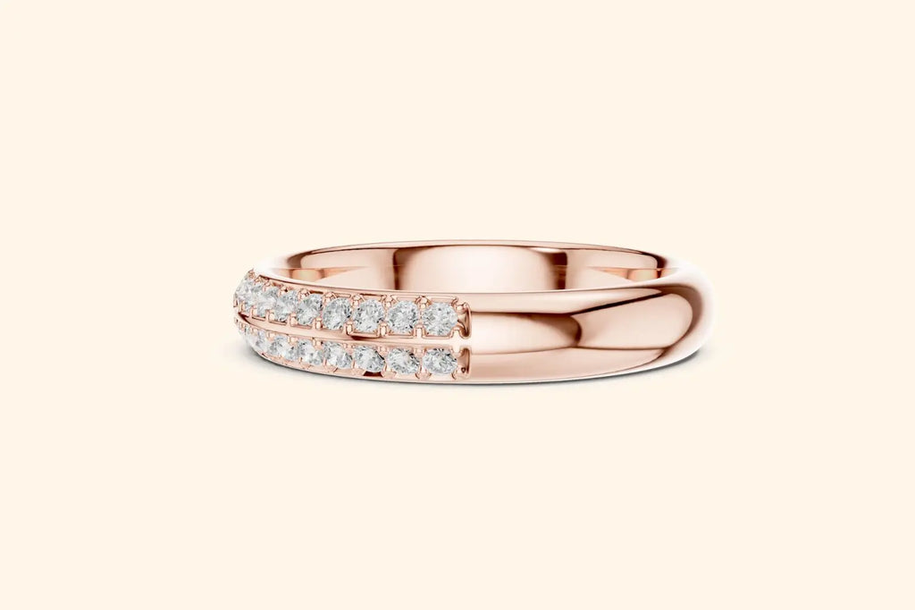 A close-up, straight-on view of a polished rose gold band ring. The top half of the ring is smooth metal, and the bottom half is adorned with two parallel rows of pave-set round diamonds.
