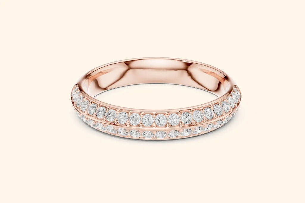 A stunning rose gold eternity band ring with two rows of pave-set round brilliant diamonds spanning the entire circumference. The metal is highly polished, and the diamonds are set closely together with minimal visible prongs. The ring has a slightly rounded profile.