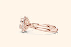 A horizontal, close-up side view of a rose gold ring showcasing the setting's detail. The diamond cluster and halo are clearly visible, supported by an intricate basket setting above the sleek, polished rose gold band.