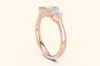 A side-profile view of a three-stone ring in polished rose gold. It clearly shows the slightly raised setting of the central emerald-cut diamond and one pear-shaped side diamond, with the narrow band curving underneath.