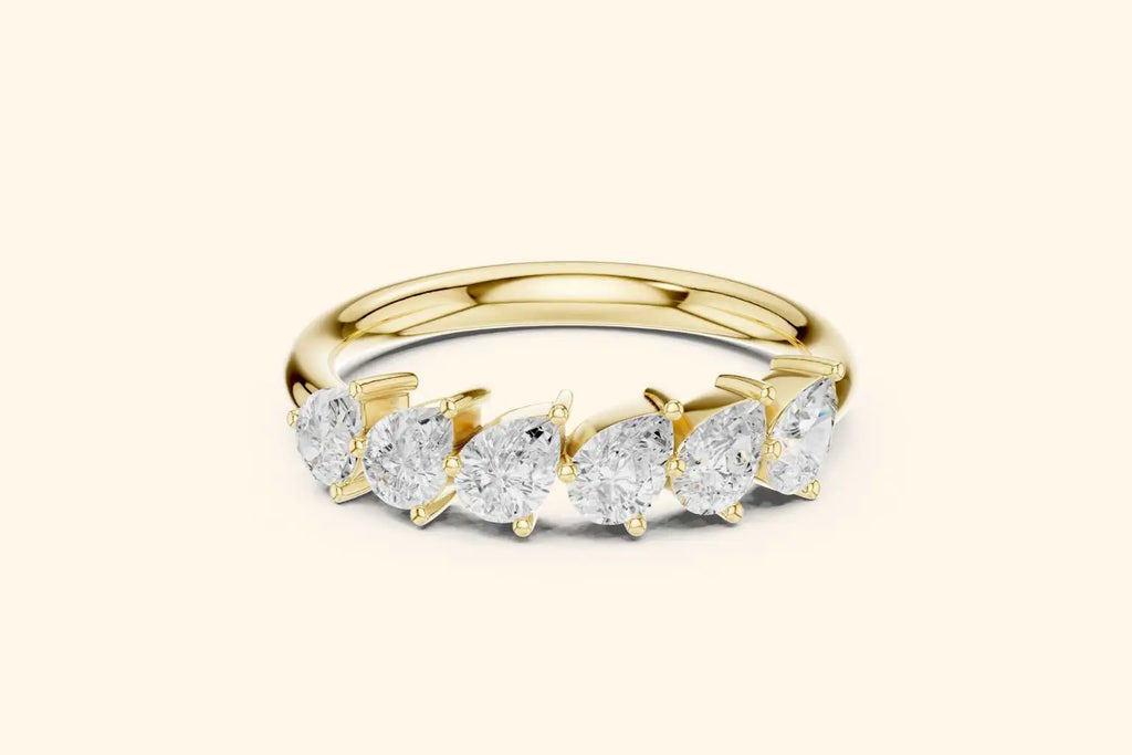 A head-on view of a sparkling half-band ring in bright gold or yellow gold. The ring showcases six graduated or similarly sized pear-shaped diamonds set side-by-side along the band, with minimal visible metal between the stones.