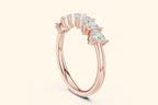 A steep angled profile view of a delicate rose gold ring. The photograph showcases the open, elevated setting for the pear-shaped diamonds, which appear to float along the slender, polished band.
