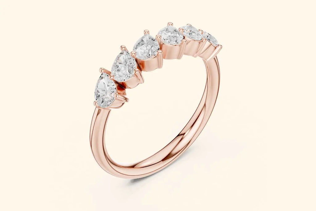 An angled view of a slender rose gold ring. The design highlights a stream of brilliant pear-shaped diamonds set horizontally and slightly elevated on the thin band, creating a dynamic, flowing look.
