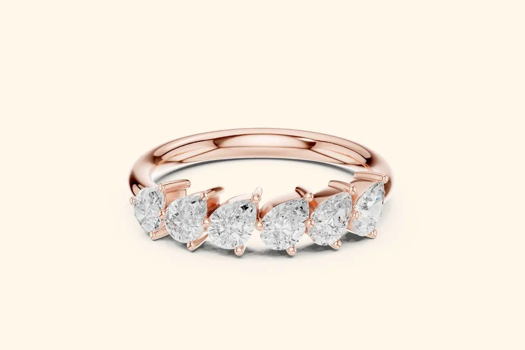 A front view of a half-band ring in polished rose gold. It features a row of six brilliant pear-shaped diamonds set horizontally along the top, with the pointed ends of the diamonds aligned in the same direction.
